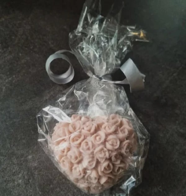 Heart-shaped arrangement of pink foam roses wrapped in clear cellophane with white ribbon bow