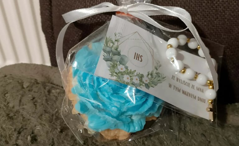 Clear gift box containing blue flower petals and white pearls with decorative white ribbon and tag