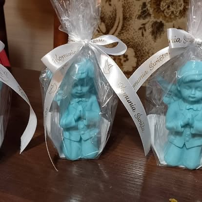 Two turquoise decorative bust sculptures wrapped in clear cellophane with white ribbon bows