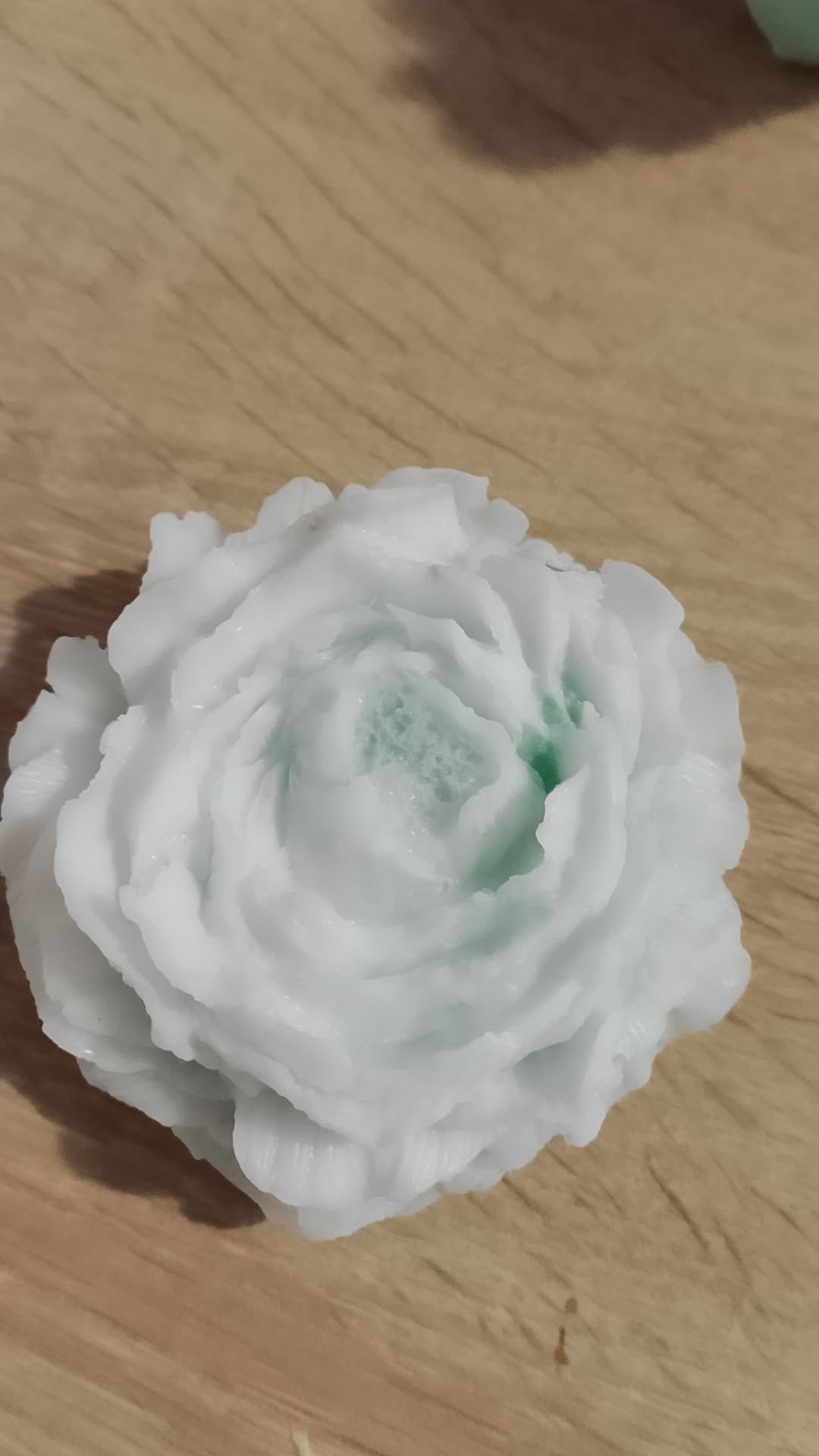 White rose with pale green center on a wooden surface